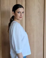 Remera blanca con cuello en V, cuerpo de algodón y mangas abullonadas de encaje bordado con puños elásticos.