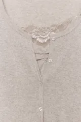 Chaqueta de punto color beige con escote en pico y manga larga, que incluye un top interior integrado con detalle de encaje a tono. Cierre frontal mediante botones.