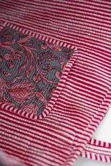 Bolso tipo tote bag de tela acolchada con estampado floral en tonos gris y blanco. Presenta asas largas reforzadas con detalle de rayas en los bordes.