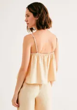 Blusa beige de tirantes finos, con escote en V y diseño fruncido tipo nido de abeja en la parte superior.
