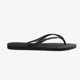 Ojotas Havaianas modelo Slim Logo Metallic, color negro, con tiras finas y logo metálico dorado. La suela es delgada y presenta textura antideslizante.