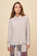 Camisa de manga larga color celeste, con cuello clásico y botonadura frontal. Presenta un calce relajado, con mangas amplias y puños anchos.