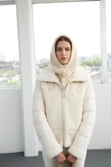 Campera de diseño híbrido en color blanco, que combina paneles acolchados en las mangas con cuerpo de gamuza sintética. Presenta cuello, puños y ruedo con detalles en piel sintética tipo corderito, cierre frontal completo y bolsillos laterales con cierre.