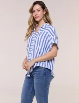 Camisa de algodón con rayas verticales en tonos verde, rosado y blanco. Tiene mangas cortas amplias, escote en V con solapa y botones frontales, y detalle de nudo en el bajo.