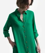 Vestido chemise largo color naranja, confeccionado en viscolino. Tiene cuello solapa, cierre con botones, manga larga con martingale, aberturas laterales y no tiene estampado.