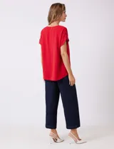 Blusa de crepe color blanco, con cuello redondo a la base y mangas cortas con detalle de presilla y botón en el borde.