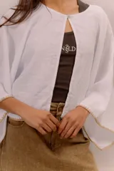 Blusa de lino color blanco, de diseño amplio con mangas murciélago y bordado decorativo en los bordes.