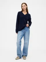 Buzo de punto con cuello en V, manga larga y puños acanalados. Diseño holgado y minimalista.