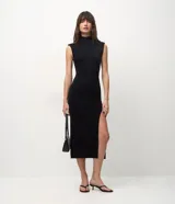 Vestido midi de punto color negro, con cuello alto, hombreras y tajo lateral. Diseño ajustado al cuerpo.