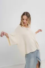 Sweater oversize de tejido liviano color blanco roto, con textura semi traslúcida, escote redondo y mangas amplias estilo murciélago.