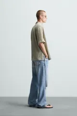 Camisa de manga corta con cuello solapa, confeccionada en tejido de mezcla de lyocell con textura de efecto arrugado y cierre frontal de botones.