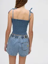 Short de denim color tostado, de corte relajado con cintura elástica y cordón ajustable. Posee un bolsillo trasero con un pequeño bordado de sol.