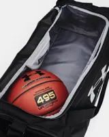 Bolso deportivo Under Armour Undeniable 5.0, color negro con logo de la marca en color dorado. Cuenta con correa ajustable para el hombro y asas de mano, ideal para transportar equipamiento deportivo.