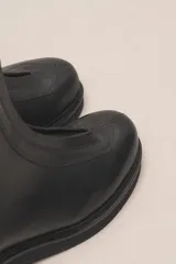 Bota corta de cuero negro con cierre frontal con cremallera y suela de goma.