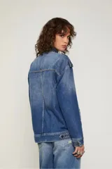 Chaqueta de jean azul con corte oversized, bolsillos con solapa en el frente, cierre metálico y detalles de desgastado suave.