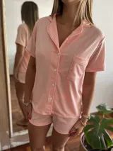 Pijama de dos piezas color rosa, con camisa de mangas cortas abotonada al frente y short.