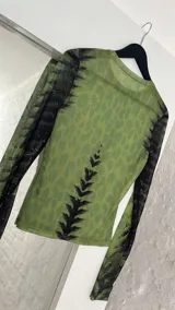 Top de microtul verde con estampado abstracto en tonos verdes y negros, de mangas largas y cuello redondo.