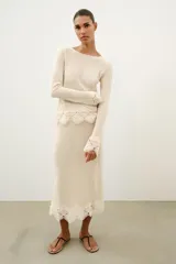 Top de tejido rústico color beige con cuello redondo y mangas largas, con aplicación de crochet a tono en los puños y el ruedo.