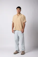 Camisa de manga corta con cuello cubano, confeccionada en lino entramado de textura natural. Presenta un corte relajado y cierre frontal con botones.