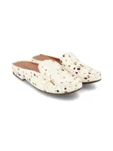 Zueco destalonado de cuero con pelo, diseño tipo mocasín abierto con estampa de animal print tipo vaca en tonos blanco, marrón y negro, y suela plana de goma.