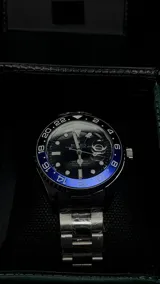 Reloj Rolex Submariner "Batman" con bisel giratorio unidireccional negro y azul, esfera negra con índices luminiscentes, lupa sobre la ventana de fecha y malla de acero inoxidable.
