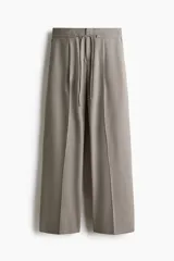 Pantalón sastre de tiro alto, color gris, con cordón ajustable en la cintura, piernas amplias con pinzas, raya marcada, bolsillos laterales discretos y bolsillos insertados atrás.