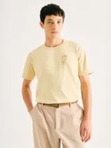 Camiseta blanca de algodón con cuello redondo y mangas cortas. Estampa rectangular con borde negro que contiene la frase "NATURAL ATMOSPHERE" en letras mayúsculas y una imagen de montañas y mar.