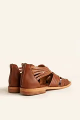 Sandalia de cuero color marrón chocolate, con suela plana y diseño calado con detalles trenzados.