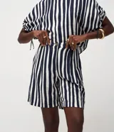 Short femenino de viscosa y poliamida, con estampado de rayas verticales blancas y azul marino. Presenta un modelo corto, cintura elástica y cierre de botón.