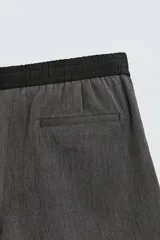 Bermuda de corte relajado color gris oscuro jaspeado, con cintura elástica negra ajustable mediante cordón negro. Presenta bolsillos frontales y bolsillos traseros de vivo.