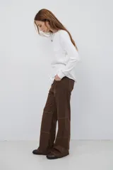 Remera de manga larga en color beige, confeccionada en tejido de punto con costuras a la vista en contraste. Presenta un corte holgado, cuello redondo y un pequeño bordado distintivo en la parte inferior.