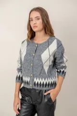 Cardigan de punto con diseño de rombos en tonos gris, blanco y negro. Presenta cuello redondo, cierre frontal con botones dorados y mangas largas.