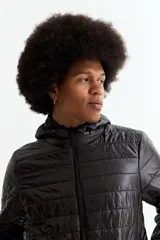 Campera puffer negra con capucha, cierre frontal completo y puños elásticos. Diseño acolchado con costuras horizontales.