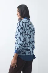 Sweater de punto con diseño estampado de hojas en tonos azul claro y azul oscuro. Presenta cuello redondo, mangas largas y terminaciones acanaladas en puños y ruedo.