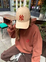 Buzo tipo canguro de calce oversize, color marrón, con cuello alto y diseño liso.