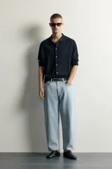 Jeans tapered wide fit de hombre, confeccionados en denim de algodón con efecto lavado en tono azul oscuro. Presentan diseño de cinco bolsillos, tiro medio, corte relajado y cierre frontal con cremallera y botón.