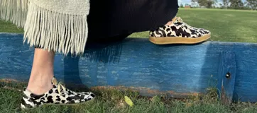 Zapatillas bajas con estampado animal print de vaca en blanco y negro, con cordones marrones y suela color caramelo.
