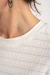 Remera blanca de manga corta con cuello redondo y textura de líneas horizontales con perforaciones.
