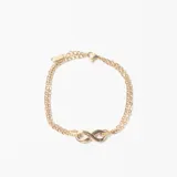 Pulsera de doble cadena fina en color dorado con dije central en forma de símbolo de infinito.