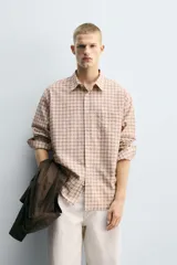 Camisa de corte relajado confeccionada en tejido fluido con algodón. Presenta un diseño de cuadros, cuello solapa, manga larga con puño abotonado, bolsillo plastrón en el pecho y cierre frontal con botones.