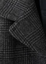 Abrigo largo estilo oversize con diseño de cuadros, cuello con solapa de muesca, cierre delantero con botones y bolsillos laterales.