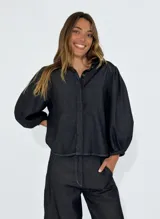 Camisa azul de denim con mangas abullonadas y cierre frontal con botones.