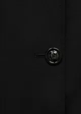 Abrigo tipo trench color negro, de diseño recto y cruzado con cierre de botones. Cuenta con cuello de solapa, mangas largas con trabillas en los puños, cinturón ajustable y dos bolsillos laterales.