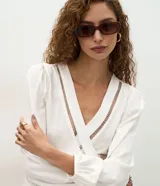 Blusa femenina tipo bata de viscosa color blanco, con escote en V cruzado y detalle calado. Presenta mangas largas con puños ajustados, corte amplio con recorte fruncido bajo el busto y diseño fluido.