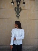 Camisa de manga larga confeccionada en broderie blanco, con diseño entallado, cuello alto y cierre frontal de botones. Presenta mangas abullonadas con hombros fruncidos y puños terminados en volados.
