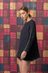 Buzo negro de tejido de punto con rayas verticales plateadas, corte holgado y mangas largas.