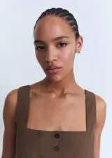 Chaleco de corte recto y diseño sin mangas, confeccionado en algodón. Presenta cuello escotado, cierre frontal con botones y dos bolsillos de ribete en la parte delantera.