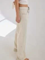 Pantalón de tiro medio alto, color beige, con bolsillos delanteros y traseros. Presenta detalles de atraques y triples costuras en color amarillo. Confeccionado en una mezcla de lino, algodón y viscosa.