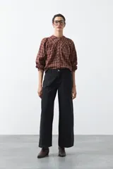 Jean de corte flare con tiro alto, color negro, con costuras verticales decorativas en el frente y bolsillos tipo cargo en la cadera.