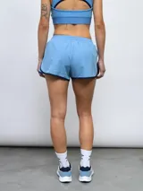 Short de entrenamiento Umbro color celeste con ribetes en azul marino y logo de la marca estampado en el frente. Presenta cintura elástica y paneles laterales de malla.